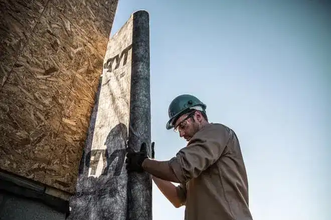 Photo of construction worker wrapping plywood on the exterior of a building with Typar building wrap